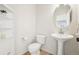 Compact powder room with pedestal sink, round mirror, white fixtures, and tiled flooring at 4844 Mt Evans St, Brighton, CO 80601