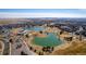 A panoramic aerial view of a community, featuring a central pond, community buildings, manicured lawns, and a network of roads at 16658 E 106Th Dr, Commerce City, CO 80022