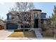 A striking two-story home with stone accents and a three car garage sits on a manicured lawn in a suburban neighborhood at 16658 E 106Th Dr, Commerce City, CO 80022