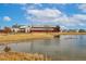 A charming scene of a pond with ducks, framed by a rustic red barn, mature landscaping, and nearby homes at 16658 E 106Th Dr, Commerce City, CO 80022