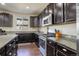 Well-lit kitchen boasts stainless steel appliances, stone countertops, and dark wood cabinets at 26881 E Roxbury Pl, Aurora, CO 80016