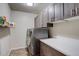 Practical laundry room featuring modern washer and dryer with overhead cabinets at 26881 E Roxbury Pl, Aurora, CO 80016