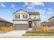 Two-story home with stone accents, gray siding, a two car garage, and a well-maintained lawn at 837 Ledge St, Lochbuie, CO 80603