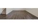 Large vacant room with dark hardwood floors and white baseboards, ideal for versatile design options at 837 Ledge St, Lochbuie, CO 80603