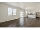 Open-concept living room with dark hardwood floors, bright natural light, and a view of the modern kitchen at 837 Ledge St, Lochbuie, CO 80603