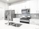 Modern kitchen featuring white cabinets, stainless steel appliances, and a spacious quartz countertop island at 22495 E 7Th Pl, Aurora, CO 80018
