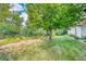 Lush backyard featuring a mature tree, grassy lawn, and a gravel area along a concrete retaining wall at 5132 Eaton St, Denver, CO 80212