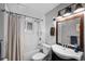 Compact bathroom with a shower-tub combo, modern fixtures, and a vintage-inspired mirror at 5132 Eaton St, Denver, CO 80212