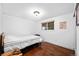 Simple bedroom with hardwood floors, a white bedspread, and natural light from the window at 5132 Eaton St, Denver, CO 80212