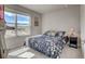 Cozy bedroom featuring a blue floral bedspread, a nightstand with a lamp, and a sunlit window at 2790 Center Park Way, Berthoud, CO 80513