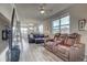Open-concept living room features gray wood floors, comfortable leather seating, and ample natural light from large windows at 2790 Center Park Way, Berthoud, CO 80513
