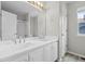 Bright bathroom features double sink vanity with white cabinets, large mirror and contemporary fixtures at 5124 S Jebel St, Centennial, CO 80015