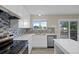 Bright kitchen features white cabinets, mosaic backsplash, stainless appliances, and a view of the deck at 5124 S Jebel St, Centennial, CO 80015