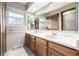 Double sink bathroom featuring wood cabinets, mirrors and tile floor at 2228 S Eldridge St, Lakewood, CO 80228