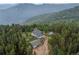 Stunning aerial view of a blue A-frame home surrounded by lush forest and breathtaking mountain scenery at 1472 Sinton Rd, Evergreen, CO 80439