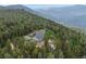 Majestic aerial view capturing a blue home nestled amidst dense forest, with rolling hills and distant mountains at 1472 Sinton Rd, Evergreen, CO 80439