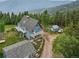 Aerial view of a gray-roofed blue house with multiple balconies and outbuildings, surrounded by trees at 1472 Sinton Rd, Evergreen, CO 80439