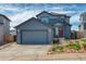 Charming two-story home with blue siding, a two-car garage, and landscaped front yard at 965 Arapahoe Cir, Louisville, CO 80027