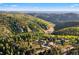 Expansive aerial view of a home nestled in a valley of lush green trees with distant mountain ranges in the background at 12291 S Critchell Ln, Littleton, CO 80127