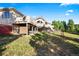 Wide shot of back of the house with lots of green grass and some trees on a sunny day at 12291 S Critchell Ln, Littleton, CO 80127