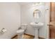 Cozy half bathroom with pedestal sink, decorative mirror, and tile flooring at 6414 S Hudson St, Centennial, CO 80121