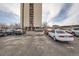 View of a parking lot filled with many parked cars in front of a tall building at 2225 Buchtel Blvd # 1003, Denver, CO 80210