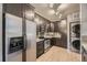 Modern kitchen features stainless steel appliances, dark cabinets, and a stacked washer and dryer at 9481 E Mansfield Ave # 301, Aurora, CO 80014