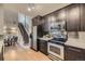 Well-lit kitchen with stainless steel appliances, dark cabinetry, and an adjacent dining area with staircase at 9481 E Mansfield Ave # 301, Aurora, CO 80014