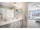 Bright bathroom boasts double sinks with elegant fixtures and a view into an adjacent bedroom at 26989 E Friend Pl, Aurora, CO 80016