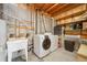 Functional basement laundry area with washer, dryer, utility sink, and wood shelving at 7350 Timber Trail Rd, Evergreen, CO 80439