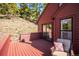 Cozy red wood deck with outdoor seating area and glass doors leading into the home at 7350 Timber Trail Rd, Evergreen, CO 80439