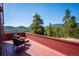 Inviting red wood deck offers stunning mountain and tree line views with seating for relaxing at 7350 Timber Trail Rd, Evergreen, CO 80439