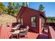 Exterior angled view of the red home and deck offers privacy and beautiful mountain views at 7350 Timber Trail Rd, Evergreen, CO 80439