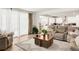 Bright living room with light wood floors, plush furniture, and seamless flow into the modern white kitchen at 27986 E Frost Pl, Aurora, CO 80016