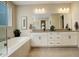 Bright bathroom featuring a soaking tub, double vanity, and neutral tile flooring at 11142 Bright Sky St, Littleton, CO 80125