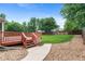 Landscaped backyard with a red deck, stone pathway, and lush green lawn at 7171 Canyon Way, Frederick, CO 80504