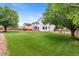 Spacious backyard with lush green lawn, mature trees, deck, playset and wooden fence at 7171 Canyon Way, Frederick, CO 80504