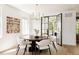 Elegant dining room with a round wood table, white chairs, and black framed glass doors at 3934 Kalamath St, Denver, CO 80211