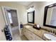 Bathroom featuring double vanity with granite countertop, framed mirrors, tile flooring, and tub with tile surround at 2525 S Pennsylvania St, Denver, CO 80210