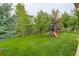 Green backyard includes a playset, lawn and mature trees at 24686 E Florida Ave, Aurora, CO 80018