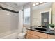 Bathroom with sleek black and white tiling above the bathtub with dual sink vanity and black countertop at 24686 E Florida Ave, Aurora, CO 80018