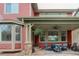 Inviting covered patio features a cozy seating area with an outdoor fire pit table, ceiling fan and stone columns at 24686 E Florida Ave, Aurora, CO 80018