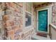 Close-up of the home's exterior featuring a teal front door and stone siding at 24686 E Florida Ave, Aurora, CO 80018