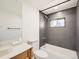 Modern bathroom featuring gray tiled shower and tub combination, with white counter tops and modern fixtures at 5951 Oneida St, Commerce City, CO 80022