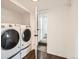 Laundry room featuring front load washer and dryer, dark wood floors and entry to the next room at 5951 Oneida St, Commerce City, CO 80022