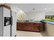 Basement kitchenette with stainless refrigerator, countertop, and dark wood cabinets at 11615 E Maplewood Ave, Englewood, CO 80111