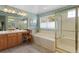Bright bathroom featuring a soaking tub, a vanity with sink and makeup area, and a glass enclosed shower at 11615 E Maplewood Ave, Englewood, CO 80111