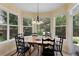 Bright breakfast nook features large windows, a chandelier, and a wooden table with seating for six overlooking a backyard at 11615 E Maplewood Ave, Englewood, CO 80111