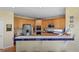 A bright kitchen featuring wooden cabinetry, stainless steel appliances, and blue-tiled countertops with a breakfast bar at 11615 E Maplewood Ave, Englewood, CO 80111