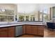 Bright kitchen featuring wood cabinets, stainless steel appliances, and a blue-tiled countertop and backsplash near large windows at 11615 E Maplewood Ave, Englewood, CO 80111